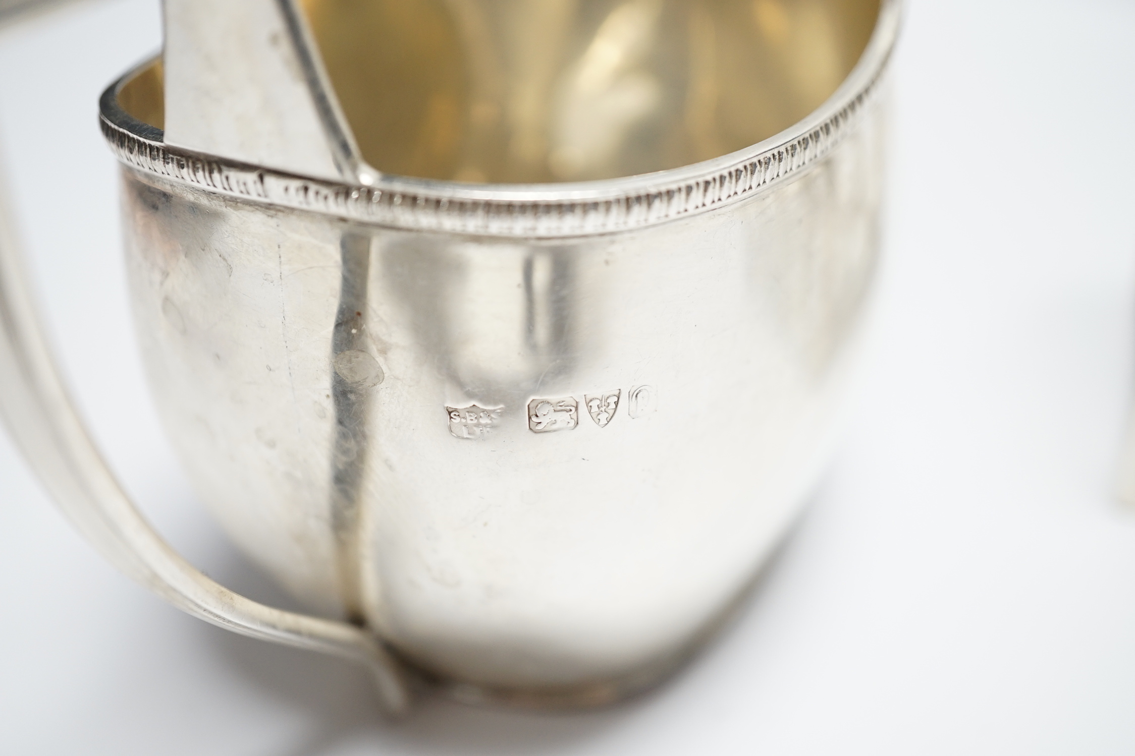 A George III engraved silver cream jug, London, 1808, height 82m, a George V silver cream jug and matching sugar bowl, and a George V silver five bar toast rack, 15.4oz.